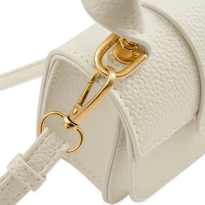 Détail attache dorée d’un mini sac à main blanc.