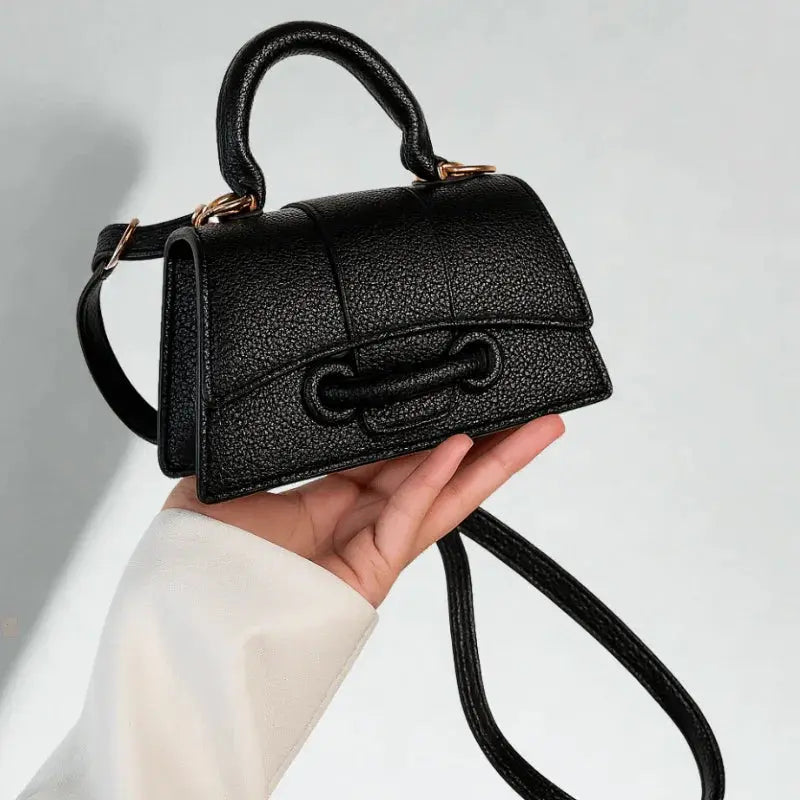 Mini sac bandoulière noir porté à la main.