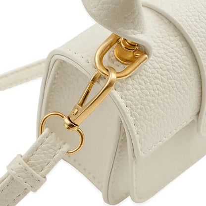 Détail attache dorée d’un mini sac à main blanc.